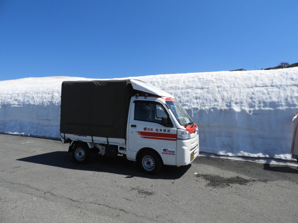 赤帽松本運送の軽貨物車両が雪道を走行する様子