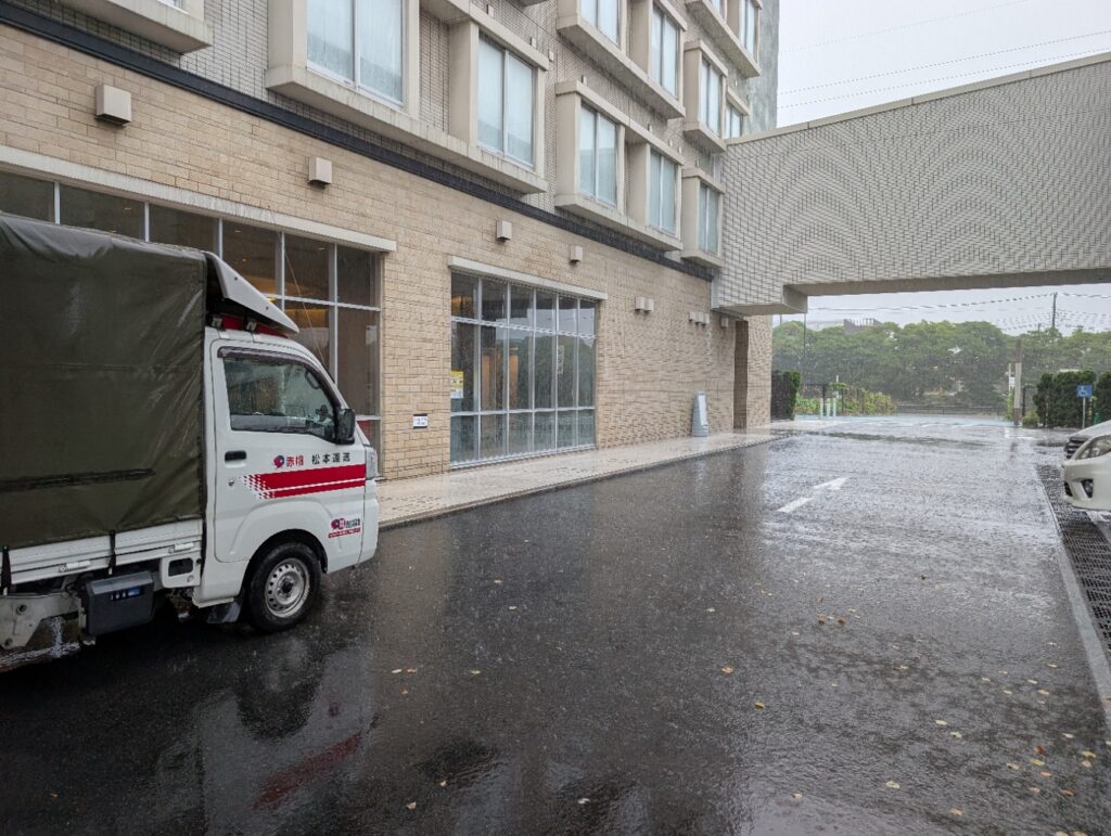 大雨の中、浦安市内のホテルで荷物を積み込む赤帽松本運送の車両