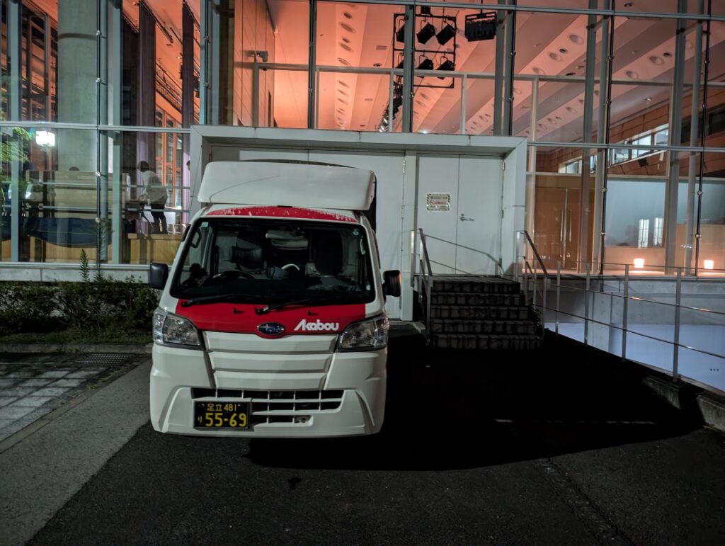 大学講堂の搬入出口で夜間にイベント機材を積込み作業中の様子