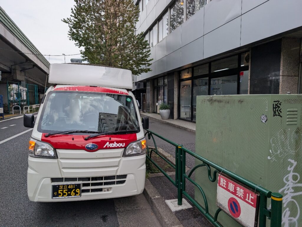 目黒区の住宅街で機材の荷下ろし作業を行う赤帽松本運送の車両