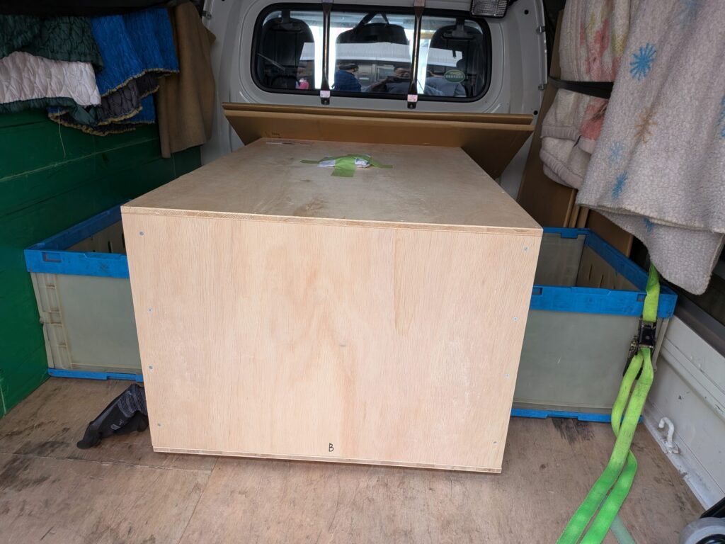 木箱を折り畳みコンテナで固定している荷台の様子