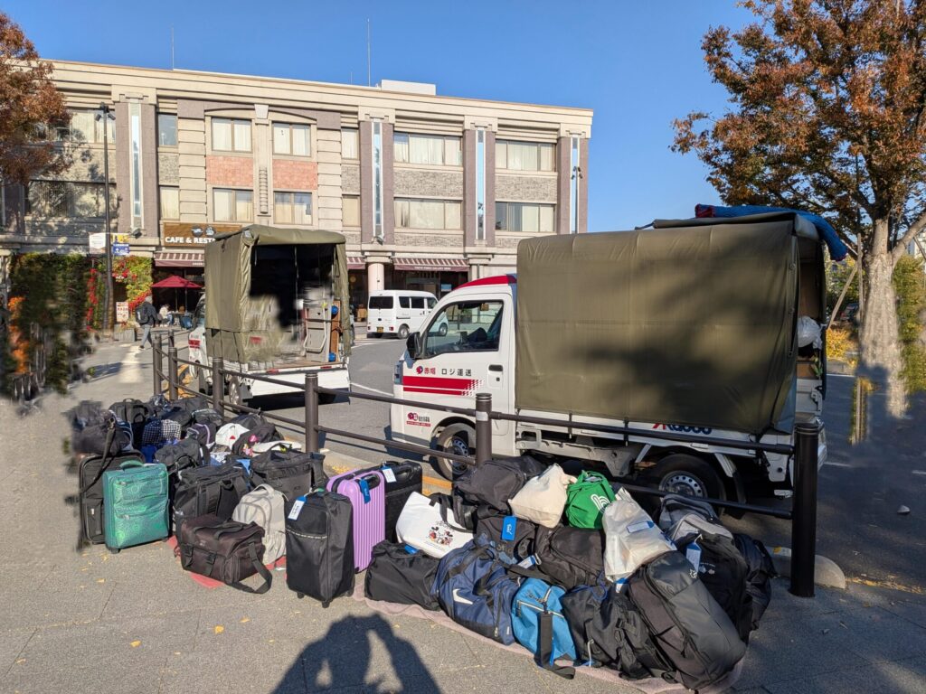 上野駅公園口で修学旅行のカバンを並べ、赤帽車2台で対応している様子