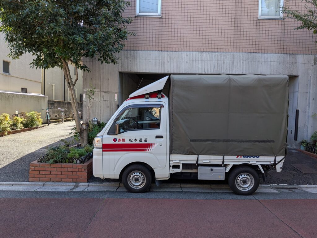 新宿区のマンション前に停車した赤帽松本運送トラック