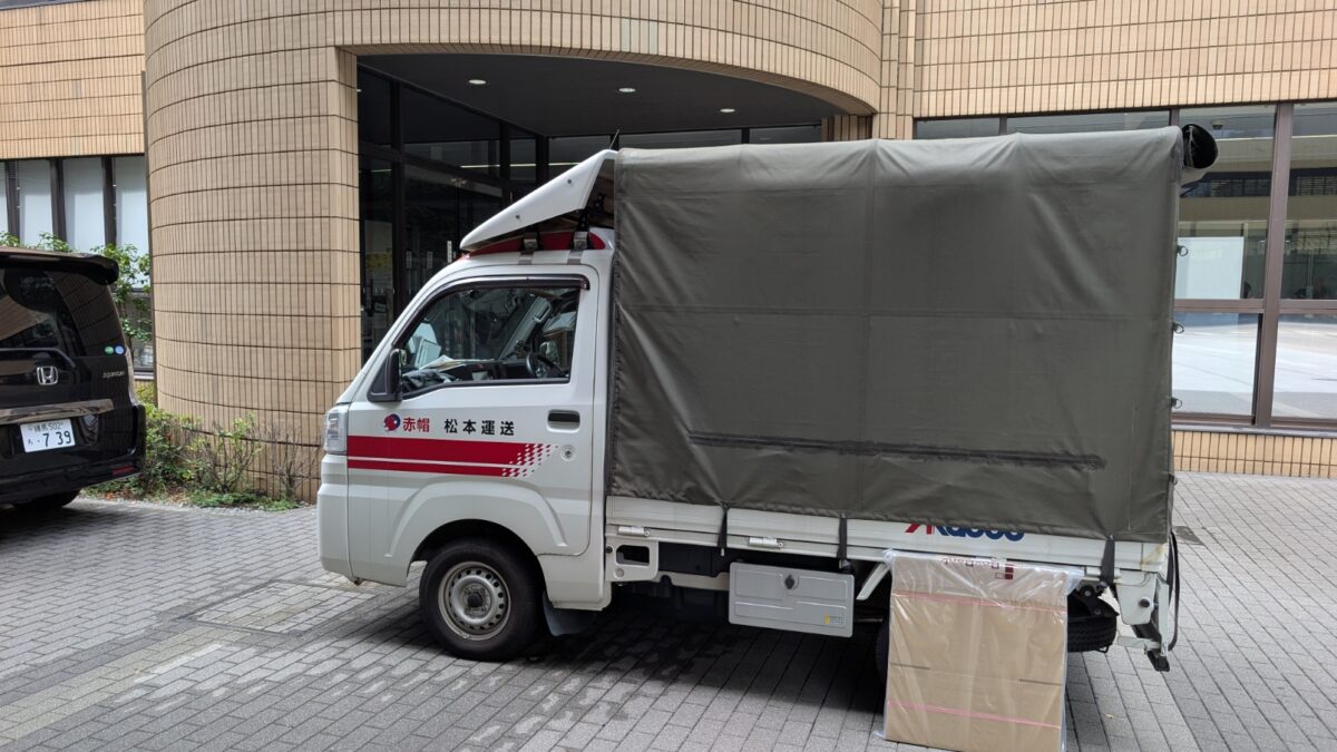 文京区の大学構内に駐車中の赤帽松本運送トラックと新品段ボール箱