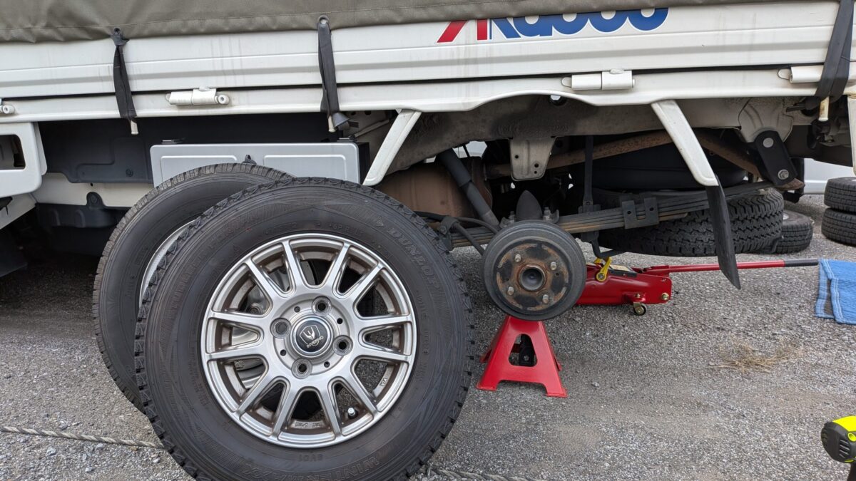 後輪交換中の赤帽トラックとスタッドレスタイヤの様子