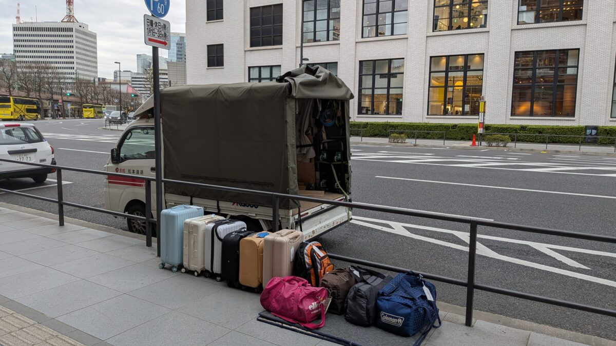 東京駅脇で修学旅行カバンを下ろし、お客様を待っている赤帽松本運送のトラック