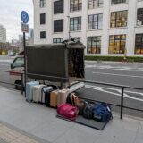 東京駅脇で修学旅行カバンを下ろし、お客様を待っている赤帽松本運送のトラック