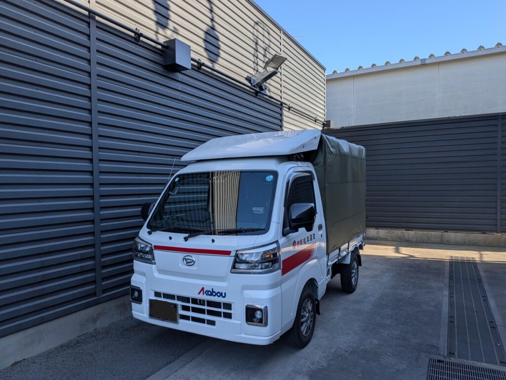 つくば市の外車ディーラーの倉庫前で荷受け待ちする赤帽松本運送の軽トラック