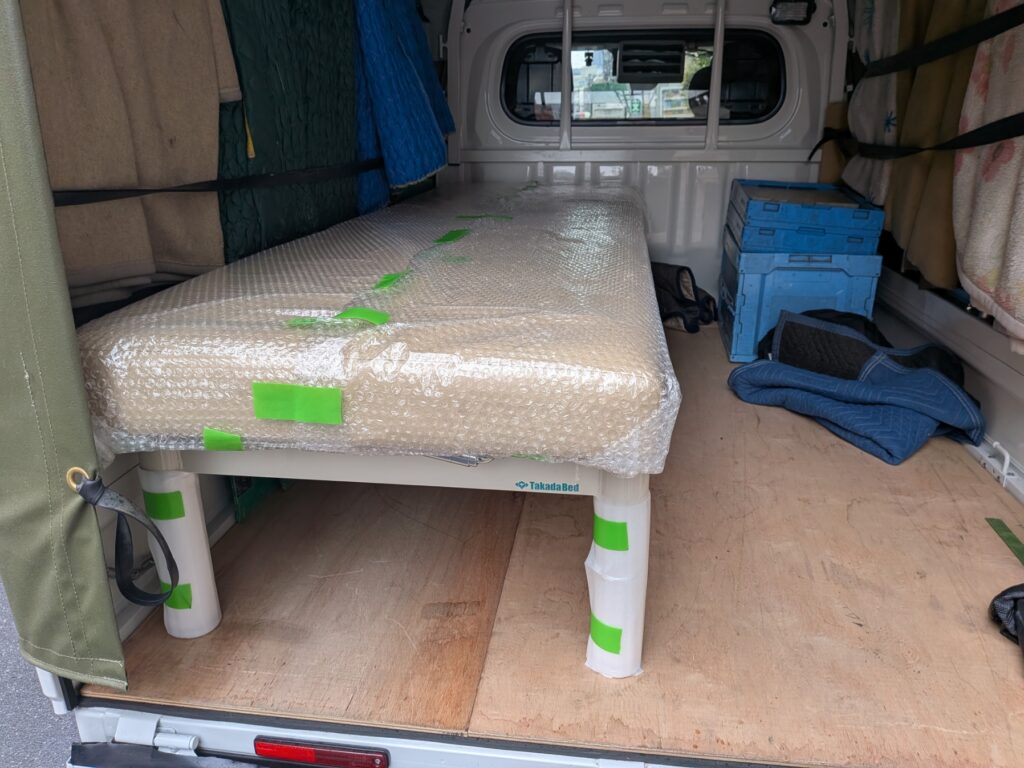 エアーキャップで梱包された治療用ベッドの積込み作業