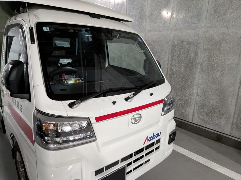 デパート地下搬入口で待機する赤帽松本運送トラック