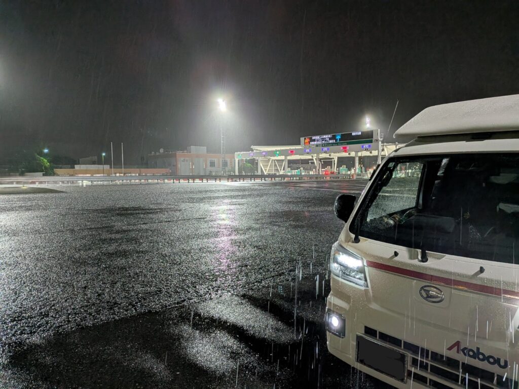 本降りの雨の中、東京料金所を通過する赤帽松本運送のトラック