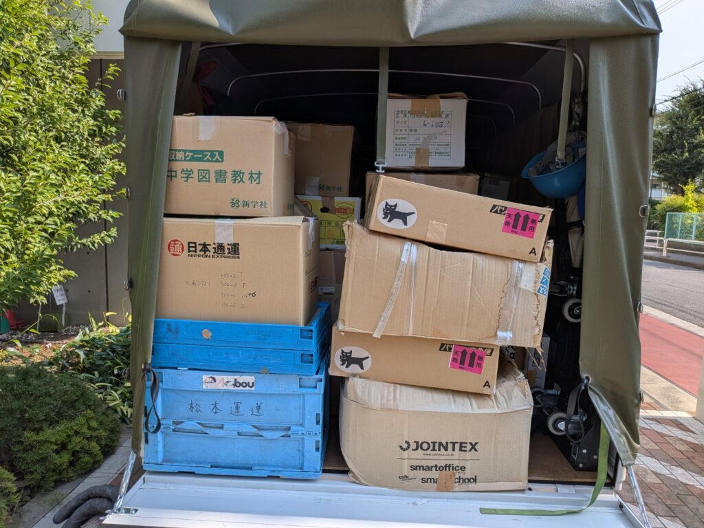 教材や資料を段ボール箱にまとめて積み込んだ赤帽松本運送トラック荷台