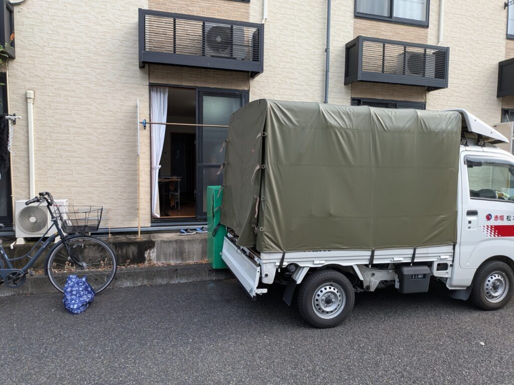 マンスリーマンション前で荷物を積込みする赤帽松本運送