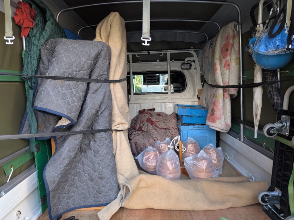 木製棚と照明をキルティングパッドや毛布で養生した赤帽トラックの荷台