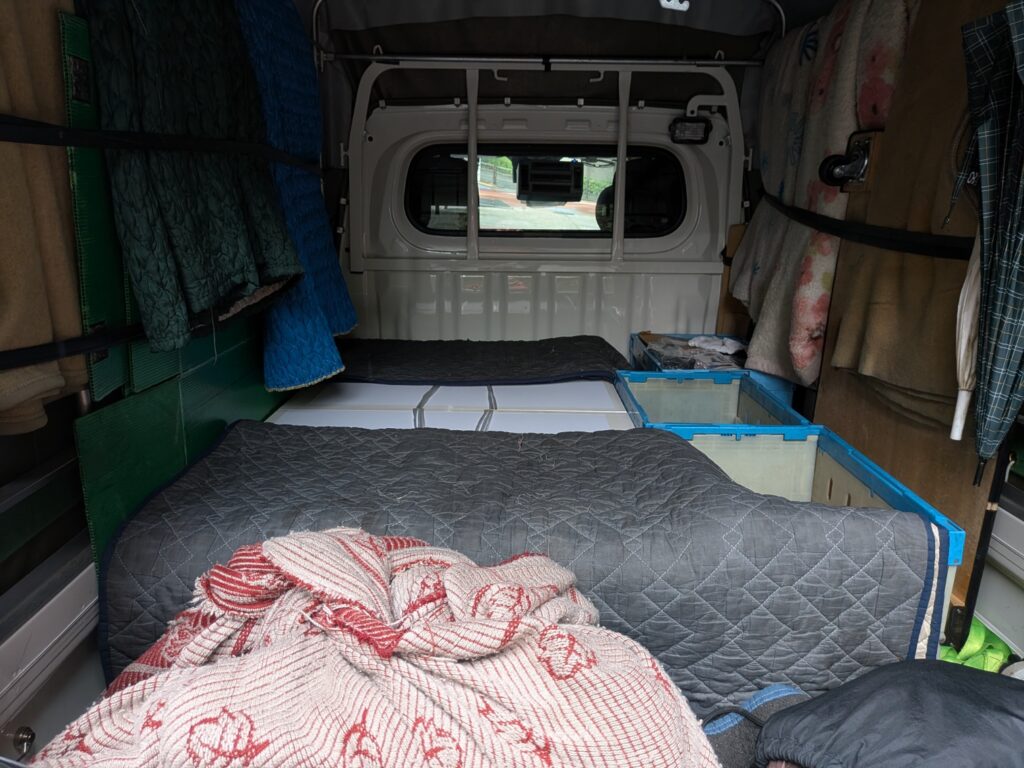 キルティングパッドで建築模型を養生しオリコンなどで固定した軽トラックの荷台