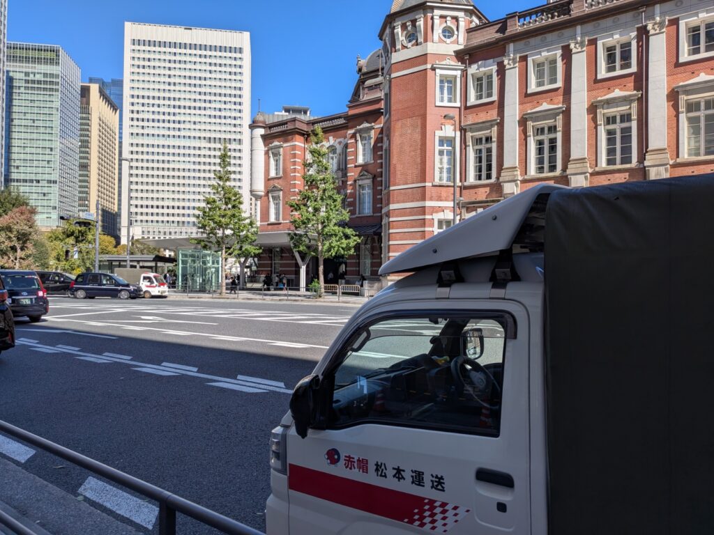 快晴の東京駅丸の内南口で修学旅行のカバンを集荷する赤帽車両
